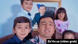 Артист Джахангир Позилжонов с детьми на фоне портрета президента Узбекистана. Кадр из видеоклипа