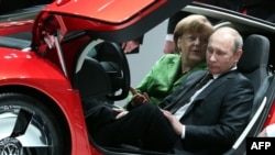 Канцлер Германии Анджела Меркель и президент РФ Владимир Путин позируют в автомобиле Volkswagen XL 1 Hybrid на выставке в Ганновере 8 апреля 2013 года 
