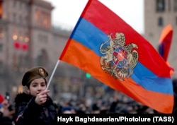A girl holds an Armenian flag during a March 1, 2021 rally on downtown Yerevan's Republic Square to support Armenian Prime Minister Nikol Pashinian.