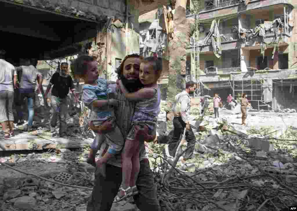 Бомбы не выбирают цели - мужчина несет своих дочерей через развалины в северном городе Алеппо, который сейчас контролируется ИГИЛом и &quot;Фронтом аль-Нусра&quot;, 17 сентября 2015
