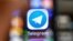 RUSSIA -- An illustration picture taken through a magnifying glass shows the icon of the popular messaging app Telegram on a smart phone screen - generic