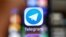 RUSSIA -- An illustration picture taken through a magnifying glass shows the icon of the popular messaging app Telegram on a smart phone screen - generic