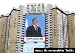 An electronic screen, installed on the facade of a Moscow shopping mall, shows an image of Russian President Vladimir Putin as he delivers his annual state-of-the-nation address on April 21, 2021.