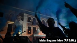 Tbilisi supporters of the ruling Georgian Dream celebrate on election night on October 2 before a campaign poster for incumbent city Mayor Kakha Kaladze. 