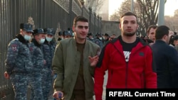 Army soldiers Aik Makhitrian (left) and Georg (no last name given) walk through a protest in Yerevan on March 1, 2021 for Armenian Prime Minister Nikol Pashinian's resignation.