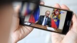 RUSSIA -- A woman watches a live broadcast of Russian President Vladimir Putin's address to the nation over the coronavirus outbreak, in Moscow on March 25, 2020