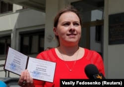Presidential candidate Hanna Kanapatskaya shows her registration certificate as she leaves the Central Election Commission in Minsk, July 14, 2020.
