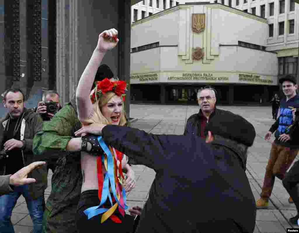 Члены крымской самообороны задерживают активистку группы Femen во время акции протеста у парламента Крыма в Симферополе. Март 2014 года
