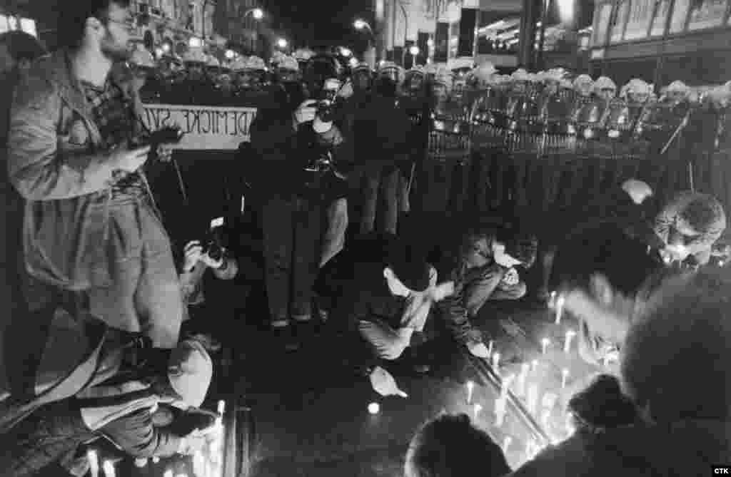 Студенты зажигают свечи у полицейского кордона. Хотя протесты были мирными, полицейские перекрыли пути отступа демонстрантам и напали на них