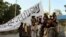 AFGANISTAN -- Taliban fighters pose for a photo on Sunday, August 15, 2021, while raising a flag in Ghazni, Afghanistan.