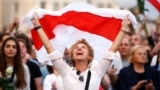 Belarus - A demonstrator reacts while holding the historical white-red-white flag of Belarus during an opposition demonstration.
