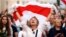 Belarus - A demonstrator reacts while holding the historical white-red-white flag of Belarus during an opposition demonstration.
