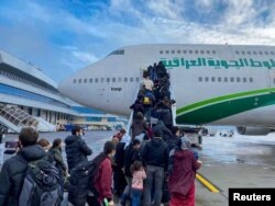 Iraqi migrants board a plane at Minsk's international airport on November 18, 2021 for an evacuation flight to Iraq.