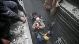 SYRIA -- Civil defence help an unconscious woman from a shelter in the besieged town of Douma in eastern Ghouta in Damascus, February 22, 2018