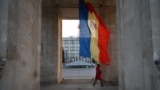A woman walks under the Triumph Arch next to Moldovan flag on Stefan Cel Mare street in Chisinau city October 8, 2013. In Moldova