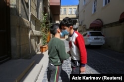 Boys shake hands on a street in Baku, the capital of Azerbaijan,after the introduction of restrictions on leaving the house in order to restrain the spread of COVID-19.
