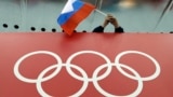 RUSSIA -- A Russian skating fan holds the country's national flag over the Olympic rings before the start of the men's 10,000-meter speedskating race at Adler Arena Skating Center during the 2014 Winter Olympics in Sochi, February 18, 2014