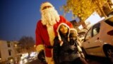 IRAN CHRISTMAS -- A girl poses for a picture with a man wearing a Santa Claus costume at a street in Tehran, Iran, 21 December 2018. 