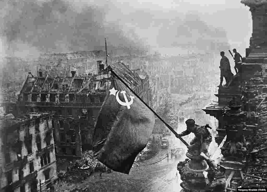 Знаковый кадр: солдат Красной армии 2 мая 1945 года поднимает советский флаг над Рейхстагом в Берлине. Этот снимок станет главной фотографией победы Красной армии над нацистской Германией, а также примером обмана советской пропаганды