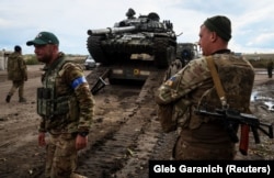 Украинские военнослужащие грузят трофейный российский танк на грузовик. Возле города Изюма Харьковской области, 24 сентября 2022 года