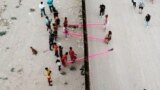 U.S. -- Children and adults play on pink seesaws, installed by Ronald Rael to symbolically bridge the divide and encourage both children and adults to play, along the U.S.-Mexico border in Sunland Park, New Mexico, July 28, 2019