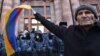 ARMENIA -- An opposition supporter waves an Armenian flag in front of law enforcement officers during a rally to demand the resignation of Prime Minister Nikol Pashinyan over a controversial peace deal with Azerbaijan that ended six weeks of war over the 