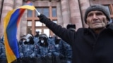 ARMENIA -- An opposition supporter waves an Armenian flag in front of law enforcement officers during a rally to demand the resignation of Prime Minister Nikol Pashinyan over a controversial peace deal with Azerbaijan that ended six weeks of war over the 