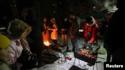 Жители одного из жилых комплексов Киева устроили вечеринку во дворе во время отключения электричества в домах из-за обстрелов армии РФ. 18 января 2026 года. Фото: Reuters