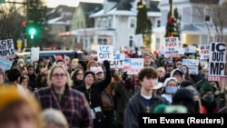 Люди держат плакаты, участвуя в траурной церемонии. На плакатах написано, в частности, "Служба иммиграции и таможенного контроля – вон", "Ни справедливости, ни мира", "Мы говорим "нет" депортациям", Миннеаполис, 7 января 2026 года