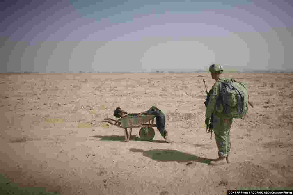 Американский солдат смотрит на тело предполагаемого боевика группировки &quot;Талибан&quot;, который погиб во время бомбардировки в Кандагаре, Афганистан. Октябрь 2010. Фото Родриго Абта