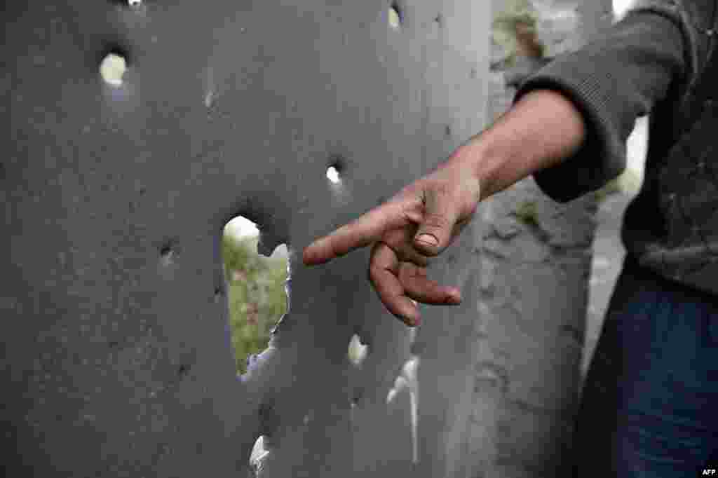 Житель азербайджанского города Тертер показывает дыры в поврежденных от обстрелов воротах