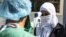SYRIA -- A medic checks the body temperature of a passenger, as a preventive measure against the coronavirus, upon her arrival by bus in Syria's Kurdish area from Iraqi Kurdistan via the Semalka border crossing in northeastern Syria, February 26, 2020
