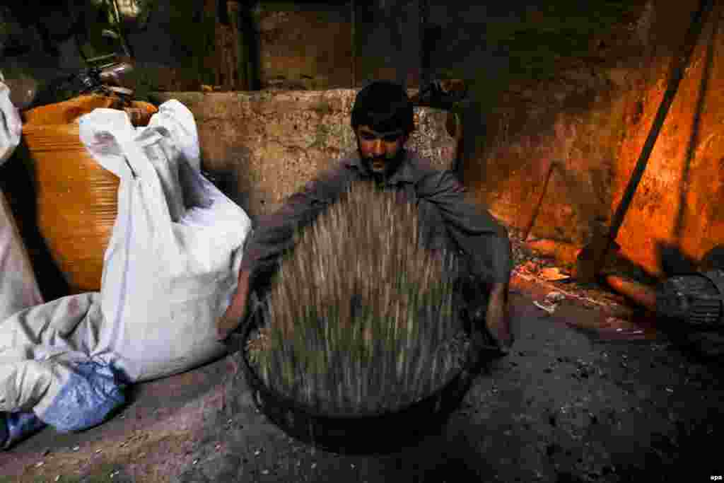 Афганский рабочий готовится жарить семена на фабрике в Герате