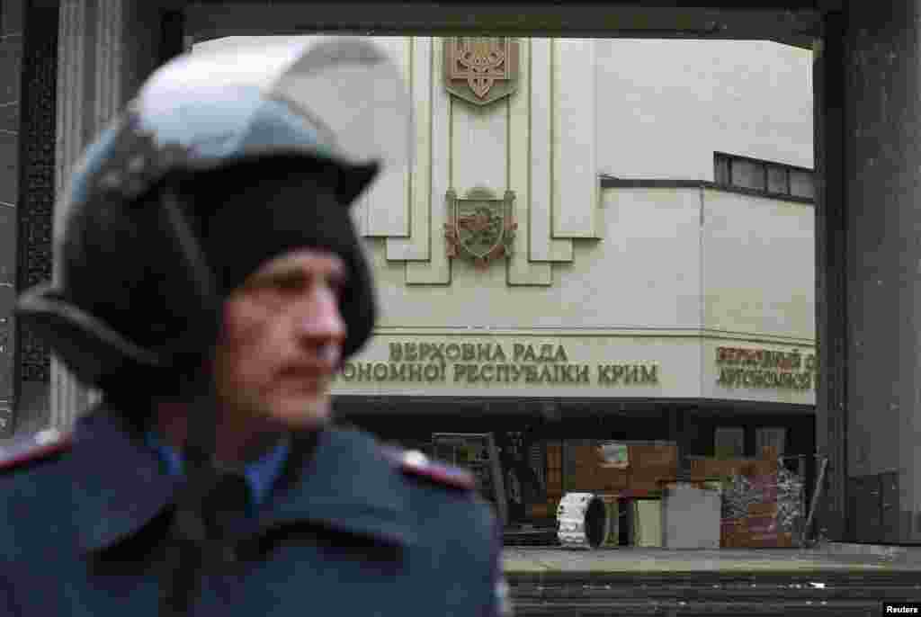Сотрудник МВД стоит возле здания крымского парламента в Симферополе, который захватили неизвестные вооруженные люди.