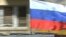 Poland -- Russian drivers, participants of the 'Roads of Glory' automobile rally, drive in their car with a Russian flag after laying flowers at the Soviet Military Cemetery in Warsaw, April 22, 2015
