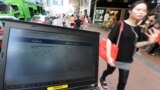 Hong Kong - A pedestrian walks past a computer showing the login page for facebook in traditional Chinese characters, 13May2012