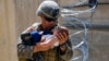 AFGHANISTAN -- A U.S. Marine assigned to 24th Marine Expeditionary Unit (MEU) comforts an infant while they wait for the mother during an evacuation at Hamid Karzai International Airport, in Kabul, August 21, 2021