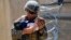AFGHANISTAN -- A U.S. Marine assigned to 24th Marine Expeditionary Unit (MEU) comforts an infant while they wait for the mother during an evacuation at Hamid Karzai International Airport, in Kabul, August 21, 2021