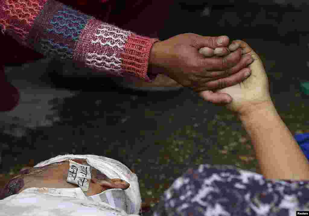 Женщина держит за руку погибшего при землетрясении родственника, Катманду, Непал&nbsp;