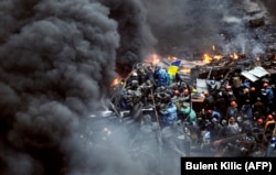 Antigovernment protesters stand behind burning barricades during a face-off against police in Kyiv on February 20, 2014.