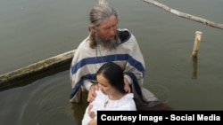Проповедник Игнатий Лапкин крестит прихожанку православной общины в деревне Потеряевка