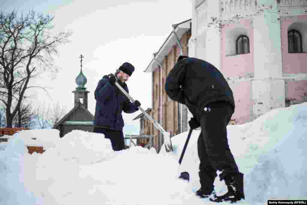 Настоятель монастыря Дионисий и прихожинин Кирилл убирают снег. Иногда Кирилл живет в монастыре неделями, участвует в религиозных церемониях и помогает с каждодневными делами