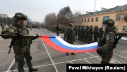 Russian servicemen fold their national flag during a January 13, 2022 ceremony in Almaty marking the beginning of the withdrawal of Collective Security Treaty Organization (CSTO) peacekeeping troops from Kazakhstan.