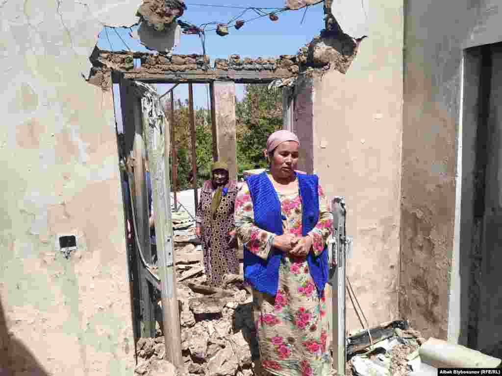 Женщина показывает дом, разрушенный во время конфликта. Село Максат в Кыргызстане
