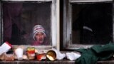 Greece -- A young migrant girl looks out the window of an abandoned building, at a refugee camp, at the border between Greece and Macedonia near Idomeni, March 15, 2016