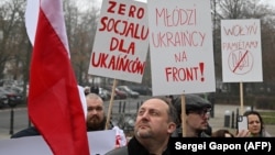 Протесты в Варшаве 19 декабря 2025 года: люди держат плакаты с надписями: "Никаких социальных льгот для украинцев", "Украинская молодежь на фронт!" и "Мы помним Волынь" (массовые убийства поляков украинскими националистами в 1940-х годах) 