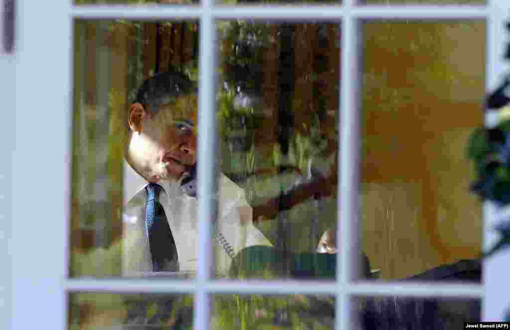 Обама разговаривает по телефону в Овальном кабинете после присуждения ему Нобелевской премии мира 9 октября 2009 года. Он был удостоен звания лауреата спустя девять месяцев после начала первого президентского срока.