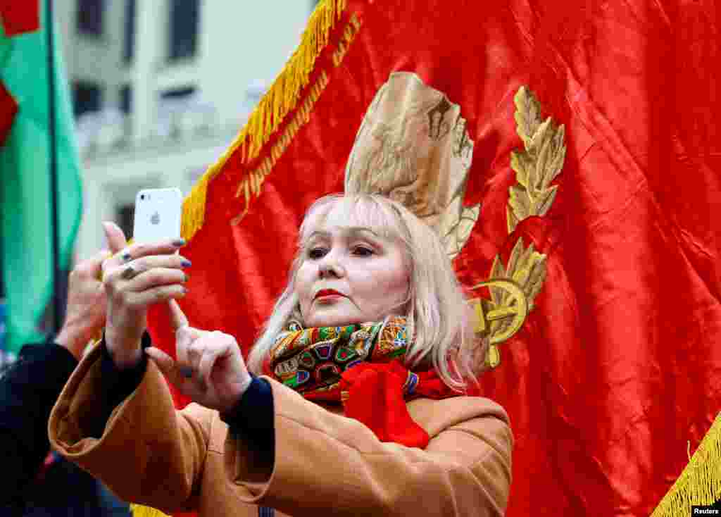 Женщина делает селфи на фоне красного флага в Минске. 7 ноября