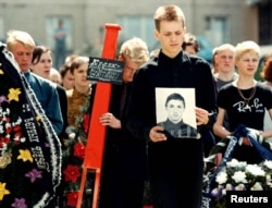 Мальчик держит портрет своего погибшего друга, 16-летнего Андрея Кулака, во время похоронной церемонии в Минске, 1 июня 1999 года