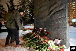 Люди оставляют цветы, свечи и фотографии возле памятника "Стена скорби" в Москве в память об Алексее Навальном. 16 февраля 2024 года. Фото: AP